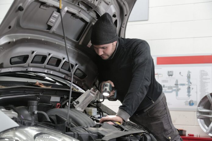 Man in Black Jacket and Black Knit Cap Inspecting Car Engine