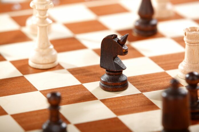Detailed shot of wooden chess pieces on a classic checkerboard, featuring a knight prominently.